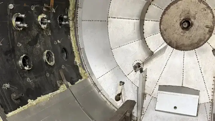 Riveted metal jacketing panels fitted over an autoclave head, mineral wool packed at the door frame.