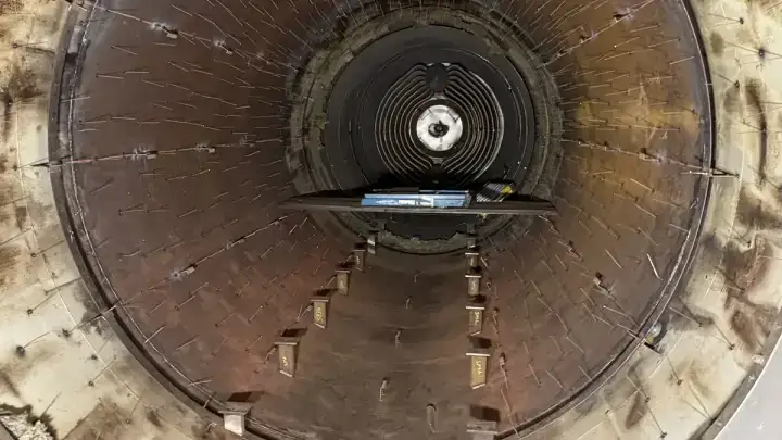 Inside an autoclave shell stripped for re-insulation, weld pins across the barrel.