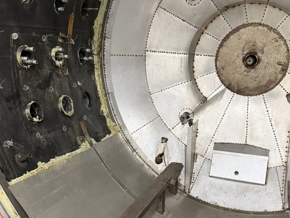 Mineral wool packed at an autoclave door frame with riveted metal jacketing panels fitted over the head.